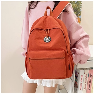 Detailed view of bright orange nylon backpack with brand logo and hidden zip pocket