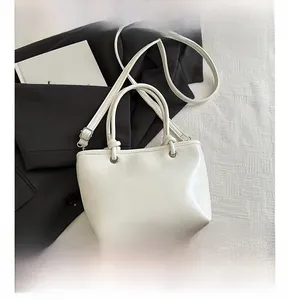 Close-up of white leather bucket bag with silver hardware and adjustable shoulder strap