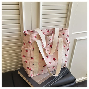 Dettaglio della borsa tote in velluto a coste rosa con stampe di fragole e manici bianchi