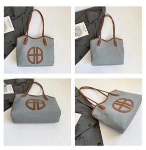 Close-up of gray woven tote bag with brown leather trim and circular letter detail