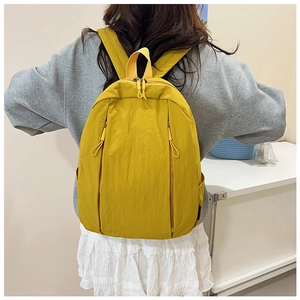 Rear view of model wearing a bright yellow minimalist backpack with double zippers