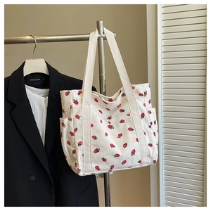 Dettaglio della borsa tote in velluto a coste bianco con motivi a fragola rossa su gruccia