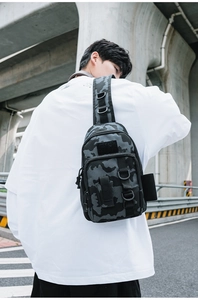 Detail of gray camouflage tactical shoulder bag showing D-rings and modular webbing straps