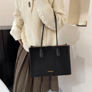Detail of black tote bag with Fashion patch, styled with knit sweater and pleated skirt