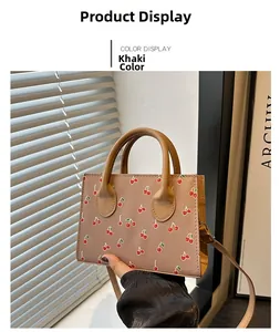 Close-up of khaki cherry print crossbody bag with sleek handles on a minimalist background