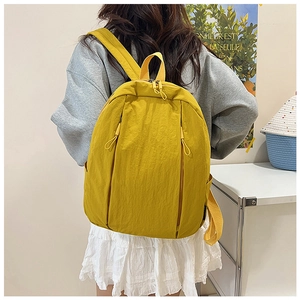 Rear view of model wearing a bright yellow nylon backpack with dual front zippers