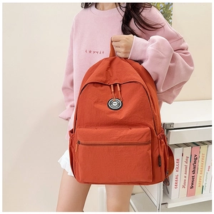 Detail view of the brick red nylon backpack with round logo and convenient side pocket