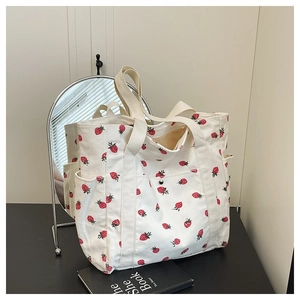 Dettaglio borsa tote in tela con stampa fragole, tasche multiple e chiusura a scatto