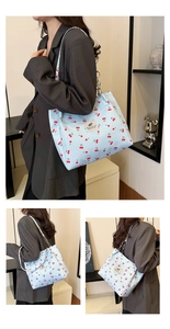 Detail of light blue cherry print canvas tote bag with chain strap and woven label
