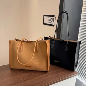 Detail of brown and black tote bags in matte suede and leather with dual straps