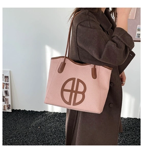 Detail of light pink woven tote bag with brown leather handles and HB logo patch