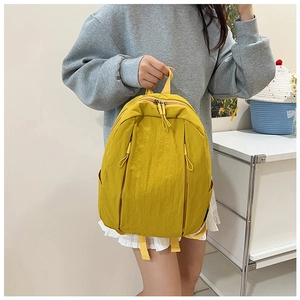 Detail view of yellow nylon backpack featuring dual vertical zippers and side pockets