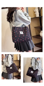 Detail view of canvas tote bag with red cherry prints and metal ring chain strap