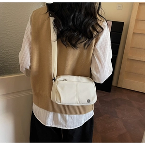 Mannequin portant le sac bandoulière en toile crème avec plusieurs poches zippées