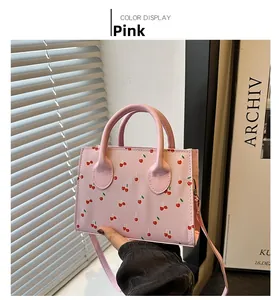 Detailed close-up of pink mini handbag with cherry prints and detachable shoulder strap