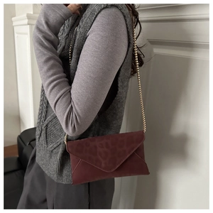 Detail view of burgundy envelope chain bag featuring leopard print embossed suede texture
