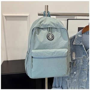 Detail view of light blue nylon backpack with front zipper pocket and side mesh storage