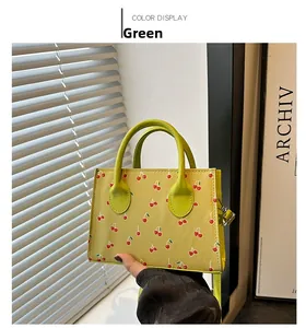 Detail view of large green cherry pattern tote bag with dual handles and crossbody strap