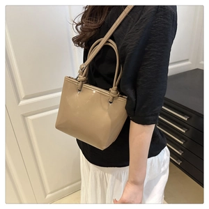 Lifestyle view of khaki leather bucket bag with knotted handles worn by a model