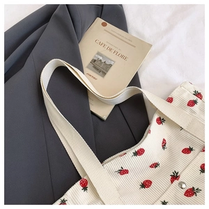 Dettaglio della borsa tote in velluto bianco con stampa di fragole e ampi manici in cotone