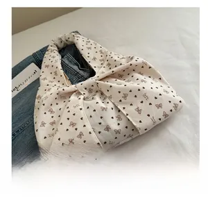 Detail of white corduroy tote bag with brown heart patterns and a large bow design