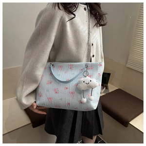 Detail of light blue floral tote bag with embossed texture and plush cloud charm
