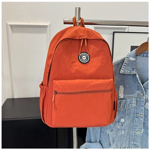 Detailed close-up of vibrant orange nylon backpack with functional front zipper pocket