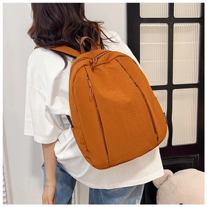 Side view of model wearing a minimalist orange waterproof nylon commuter backpack