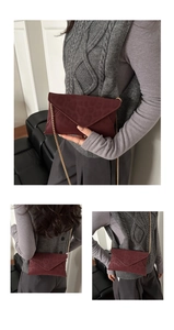Detail of burgundy leopard embossed envelope crossbody bag with gold chain strap worn by model