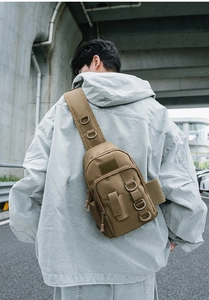 Detail of khaki tactical shoulder bag showing D-rings and Oxford fabric on model back