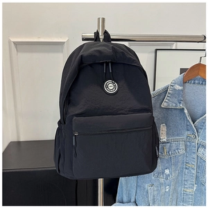 Detail of minimalist black nylon backpack with front zipper pocket and round brand logo