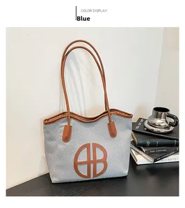 Detail of woven tote bag featuring brown leather handles and circular AB logo design