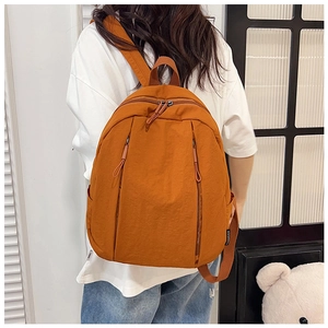 Caramel orange canvas backpack showing the adjustable straps and zipper details in use