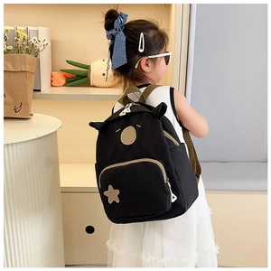 Detail view of cute black kids backpack with ear decor and star patch on a young model