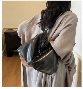 Close-up of black leather hobo bag with silver buckle and adjustable shoulder strap