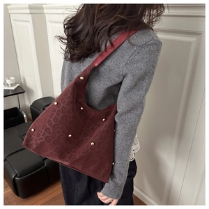 Close-up of deep red leopard embossed hobo bag featuring golden rivet design and texture