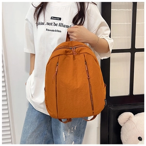 Detailed side view of orange minimalist backpack with functional zippers and water bottle pocket