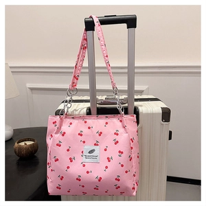 Detailed close-up of pink shoulder bag with red cherry prints on a suitcase handle