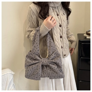 Detail of greyish-purple corduroy shoulder bag with oversized bow and heart patterns