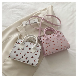 Close-up of pink and white mini tote bags featuring red cherry prints and PU leather details