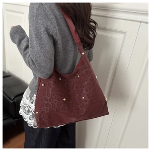 Detail of burgundy leopard embossed leather hobo bag with gold rivet studs and wide strap
