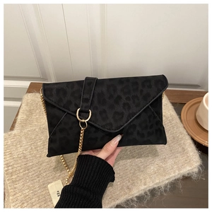 Detail of black leopard print envelope bag with gold chain strap in casual setting
