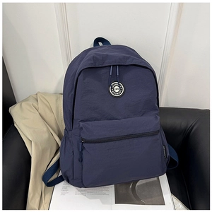 Close-up of a navy blue casual backpack featuring a round brand logo and side pockets
