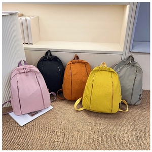 Detailed row of various colored nylon backpacks featuring hidden dual zipper front pockets