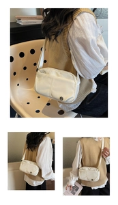 Détail d'un sac bandoulière minimaliste crème avec logo métallique et surpiqûres