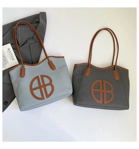 Flat lay of woven tote bags in light blue and dark grey with leather handles and B logo