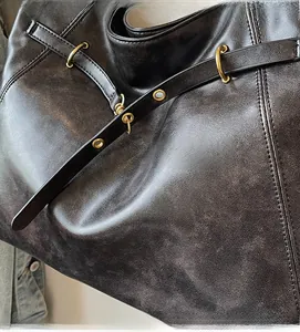 Detail of vintage brown leather tote showing gold metal rings and decorative stitching