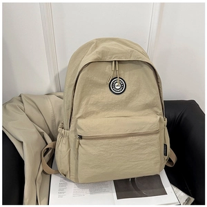 Close-up of khaki minimalist backpack on a magazine with double zippers and round logo