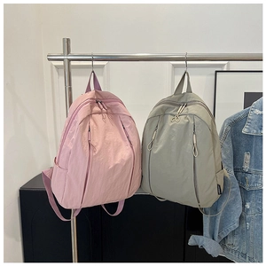 Detail of minimalist pink and green waterproof nylon backpacks with vertical zippers