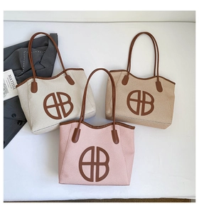 Detailed view of woven tote bags in cream, khaki, and pink with brown leather handles